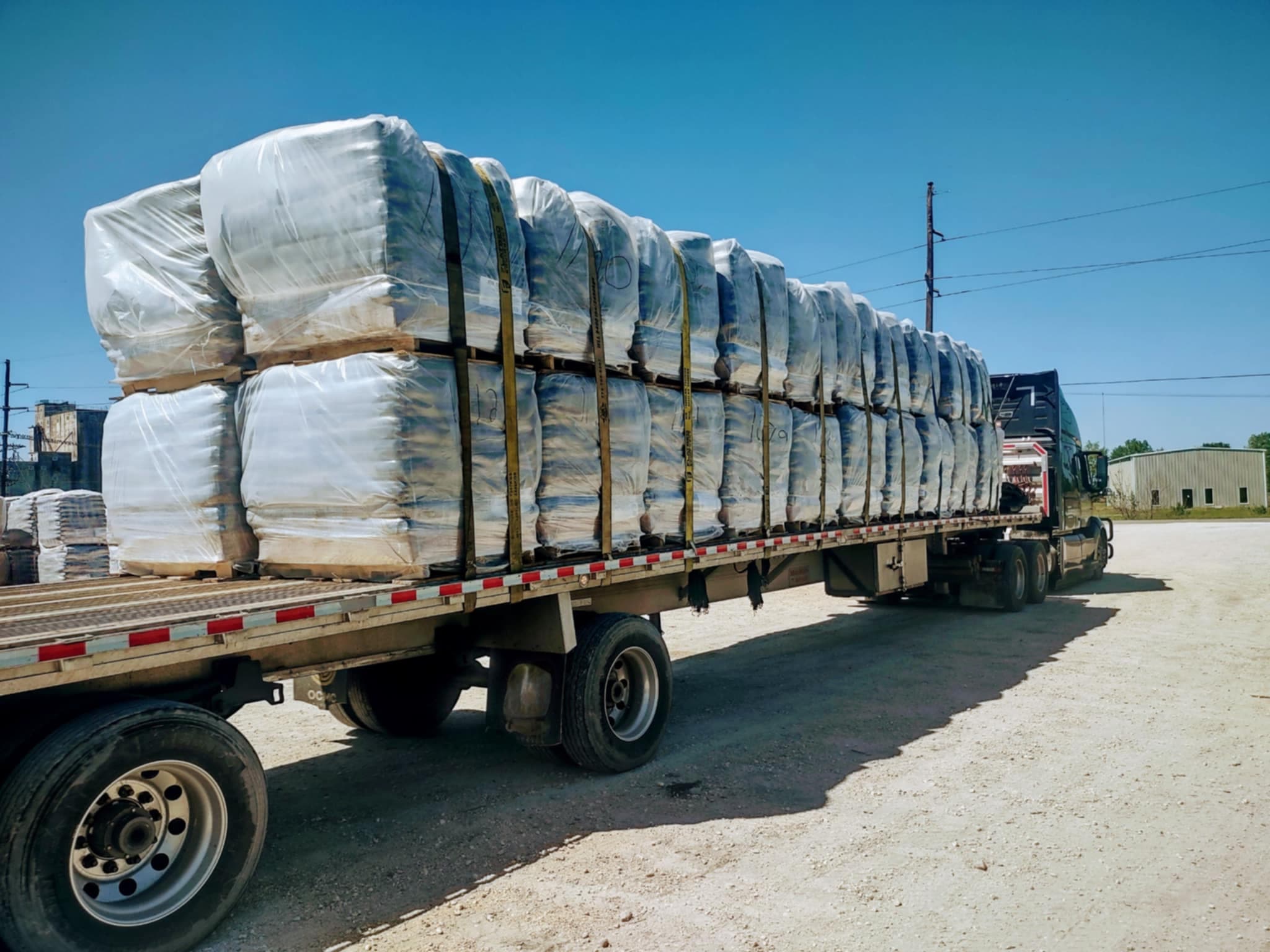 Palletized open-deck freight secured on a flatbed trailer