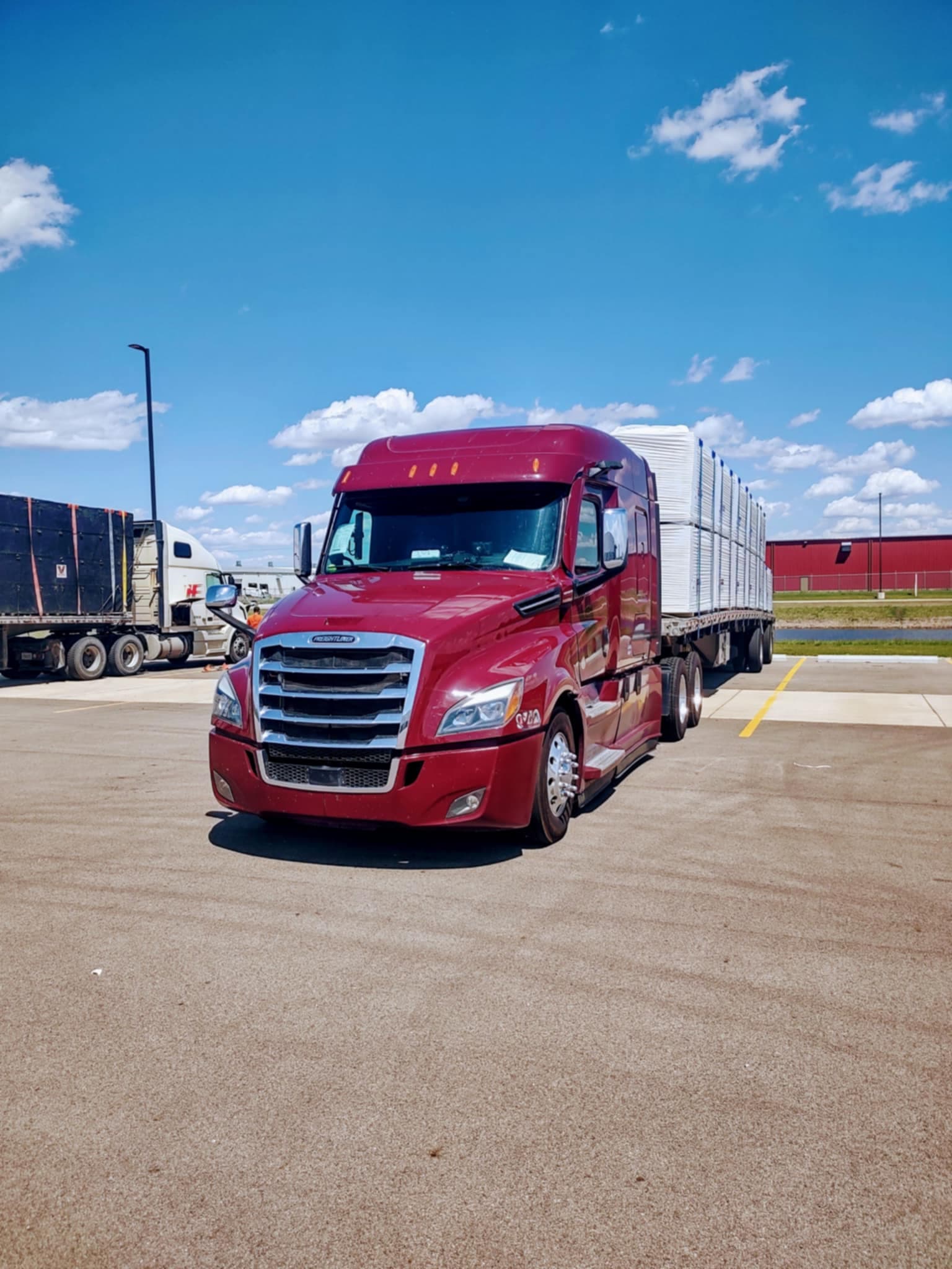 IHVI LLC semi-truck and flatbed trailer carrying wrapped building materials