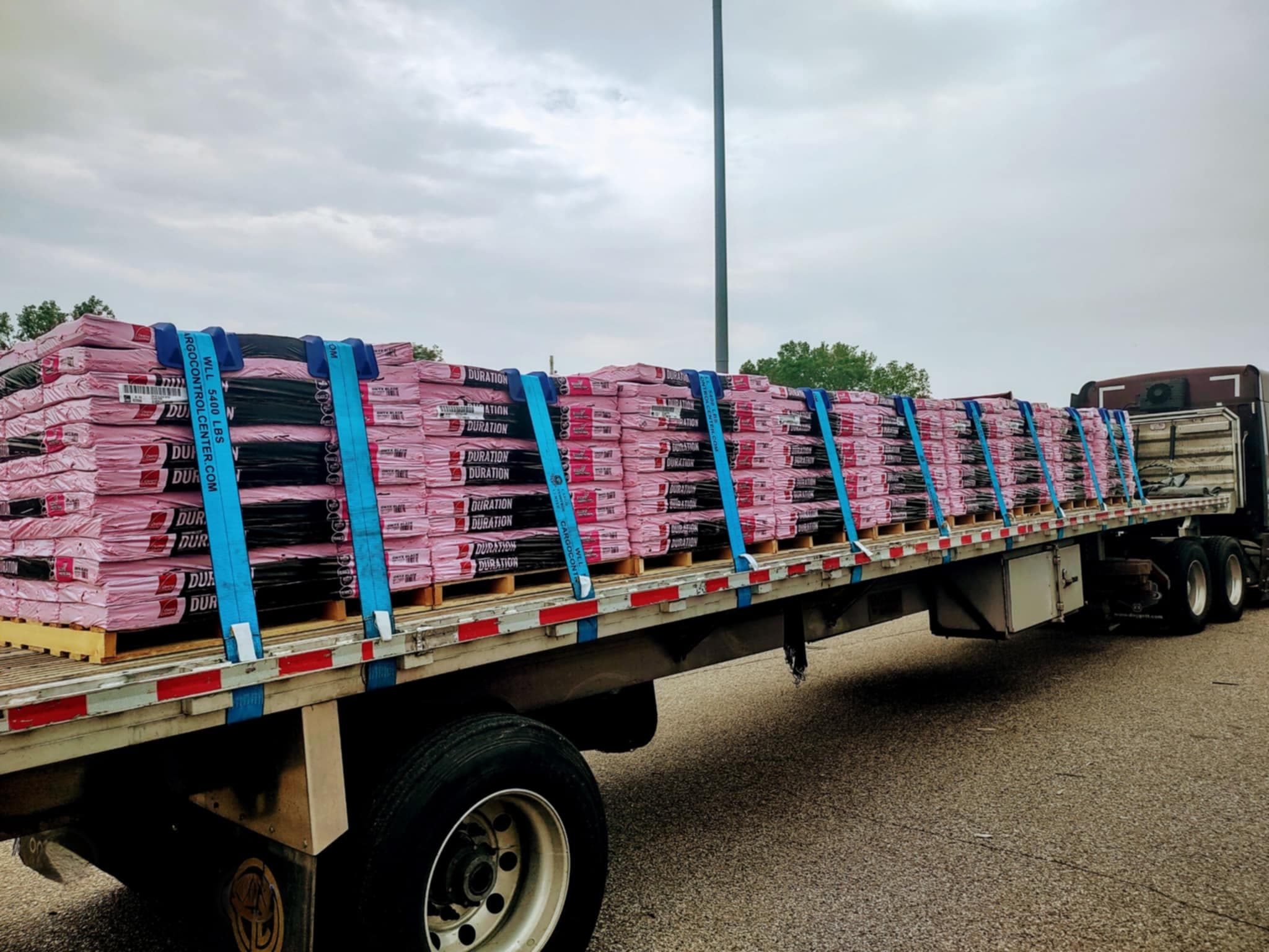Flatbed trailer loaded with construction materials secured with straps